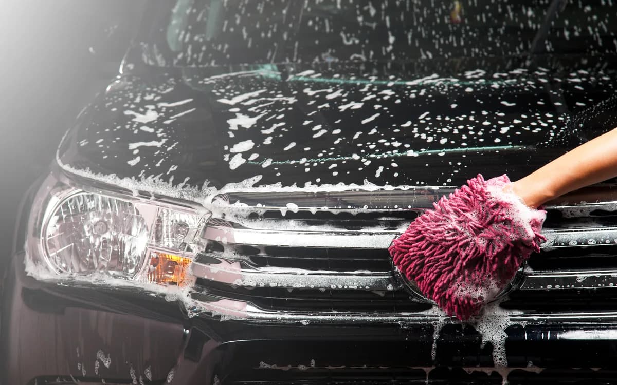 Car bodywork being hand washed with soapy water
